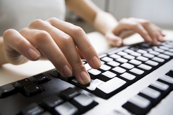 Close-up of female hands touching buttons of black computer keyboard